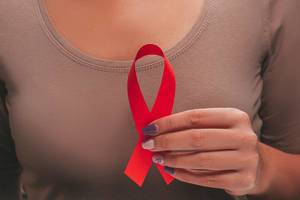 Aids Bewusstsein - Damenhand hält eine rote AIDS Schleife