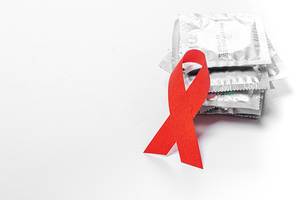 AIDS red ribbon and condoms on a white background. The concept of protection AIDS (Flip 2019)