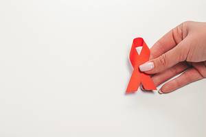AIDS ribbon in hands on white background