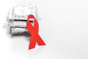 AIDS rote Schleife und Kondome vor einem weißen Hintergrund - das Konzept der Verhütung und den Kampf gegen AIDS