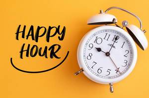 Alarm clock with handwritten Happy Hour text on yellow background