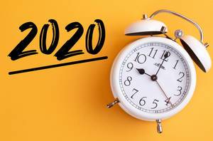 Alarm clock with handwritten text 2020 on yellow background