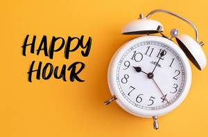 Alarm clock with handwritten text Happy Hour on yellow background