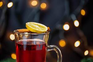 Alkoholisches Weihnachtsgetränk mit Zitrusfrucht und Gewürzstange