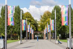 Allee mit Regenbogenflaggen vor dem Rhein-Energie Fußballstadion in Köln: gemeinsam für Vielfalt und LGBTQ-Rechte beim "Lebe wie du bist" Aktionstag