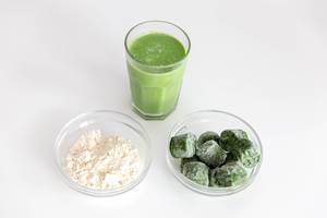 Almond protein powder and frozen spinach in glass bowls: healthy ingredients for a homemade high-energy smoothie