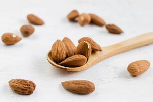 Almonds close up on a white wooden table with a spoon