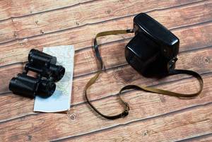 Alte Kamera und Fernglas mit Landkarte auf dem Holzboden