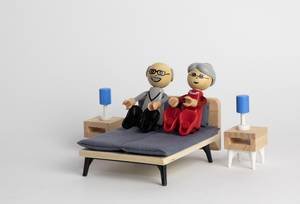 Älteres Paar liegt freudig in hölzernen Miniatur-Puppenbett - Makroaufnahme zentral