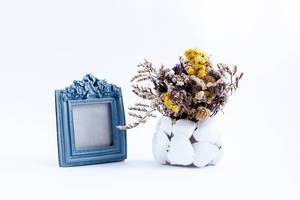 Altmodischer Fotorahmen und eine Vase mit ausgetrockneten Blumen