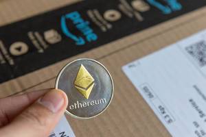 Amazon Cloudsystem templates for Ethereum-based blockchain solutions - Hand holds silver and gold-coloured Ethereum coin with diamond logo in the middle