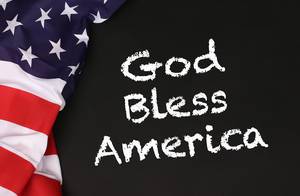 American flag with the text God Bless America against a blackboard background