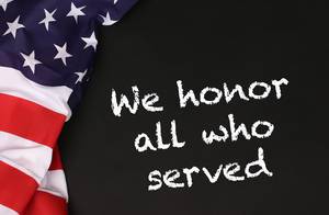 American flag with the text We honor all who served against a blackboard background