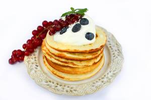 Amerikanische Pancakes mit Sahne, Blaubeeren und roten Johannisbeeren