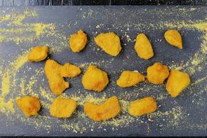Amerikanisches Fast Food: Chicken Nuggets Stücke auf einem dunklen Brettchen