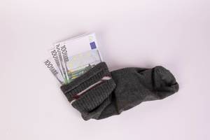 An old woolen sock full of Euro money on a white background