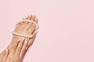 An unrecognizable woman hands with cute manicure holding pearls necklace bright pink background. Manicure and beauty concept.jpg