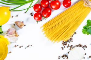 Angerichtete Zutaten für Spaghetti wie Pasta, Tomaten, Knoblauch, Pfeffer, Zitrone und Kräuter