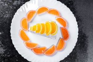 Ansicht von oben auf einen Limonenkuchen mit gezuckerten Orangenscheiben, auf einer schwarzen Arbeitsfläche