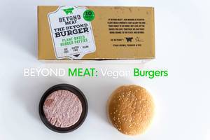 Ansicht von oben auf veganen, gefrorenen Burgerpatty von Beyond Meat, neben sojafreien und glutenfreien Burgerbox, für pflanzliche Ernährung