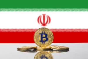 Arrangement aus vier goldenen Bitcoin-Münzen vor der Nationalflagge des Iran