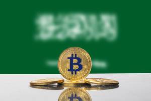 Arrangement mit vier goldenen Bitcoins vor der Flagge von Saudi-Arabien