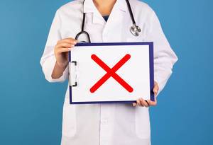 Arzt hält ein Schild mit einem roten X