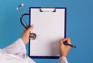 Arzt mit einem Stethoskop in der Hand schreibt auf ein leeres Schild mit blauem Hintergrund