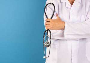 Arzt mit Stethoskop vor blauen Hintergrund
