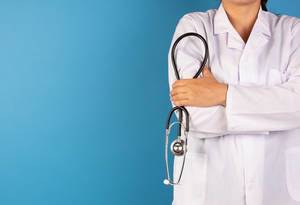Ärztin mit Stethoskop vor blauem Hintergrund