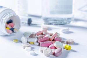 Ärztliches Behandlungsset mit Spritze und unterschiedlichen Medikamenten auf weißem Tisch