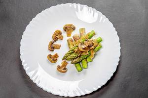 Asparagus with mushroom sauce on a white plate on a black background. Top view (Flip 2019)