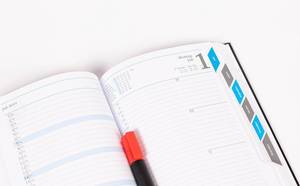 Aufgeschlagener Notizkalender mit rotem Stift für wichtige Termine
