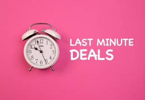 Aufschrift "Last Minute Deals",  neben einem weißen Vintage-Wecker, auf pink-blauem Hintergrund