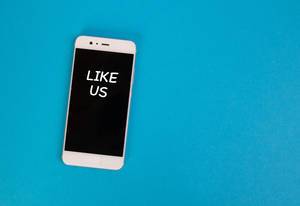 Aufschrift "Like Us" - Gib uns ein Like - auf dem schwarzen Display eines Smartphones