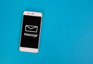 Aufschrift "Message" - Nachricht - mit einem Briefumschlag, auf dem schwarzen Display eines Smartphones