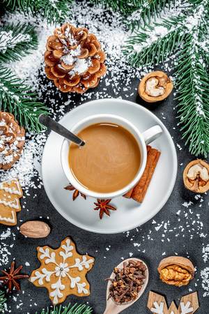Aufsicht auf eine Tasse Kaffee mit Tannenzapfen und Zweigen, Nüssen und Plätzchen in Weihnachts-Fest-Dekor