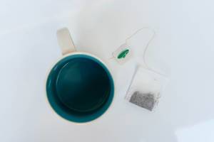 Aufsicht auf eine Tasse mit Teebeutel daneben liegend auf weißem Hintergrund