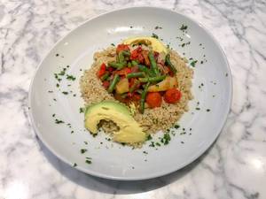 Aufsicht auf Quinoa Mahlzeit mit blanchiertem Gemüse mit Avocado un Petersilie auf einem weißem Teller
