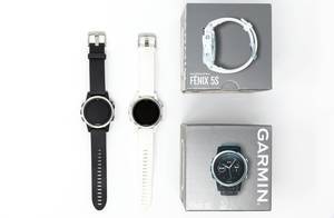 Aufsicht von Garmin Fenix 5S Smartwatches in schwarz und weiß mit Verpackung auf weißem Hintergrund