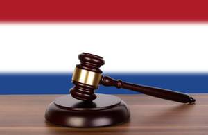 Auktionshammer / Richterhammer auf einem Holzuntergrund, vor der Flagge der Niederlande