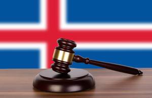 Auktionshammer / Richterhammer auf einem Holzuntergrund, vor der Flagge von Island