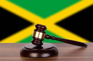 Auktionshammer / Richterhammer auf einem Holzuntergrund, vor der Flagge von Jamaika
