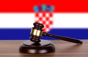 Auktionshammer / Richterhammer auf einem Holzuntergrund, vor der Flagge von Kroatien