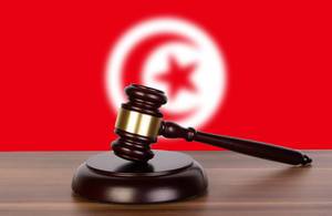 Auktionshammer / Richterhammer auf einem Holzuntergrund, vor der Flagge von Tunesien