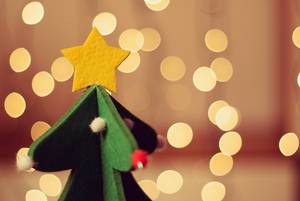 Aus Filz hergestellter Weihnachtsbaum mit Stern auf der Spitze vor Lichtermeer