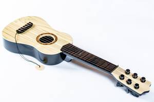 Aus hellbraunem Holz gefertigte, liegende Gitarre vor weißem Hintergrund