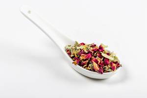 Australian green tea with flowers in a spoon on a white background