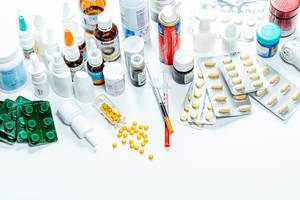 Auswahl von Arzneimitteln in Blistern und Fläschchen, lose Kapseln und Spritzen vor weißem Hintergrund