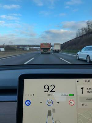 Autopilot-Funktionalität bei einem Tesla Auto: Bildschirm zeigt aktuelle Geschwindigkeit, Geschwindigkeitsbegrenzung, Reichweite in Km, Fahrzeugen auf den verschiedenen Spuren auf der Autobahn